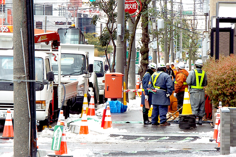 初雪が積る道路で作業する建設業者