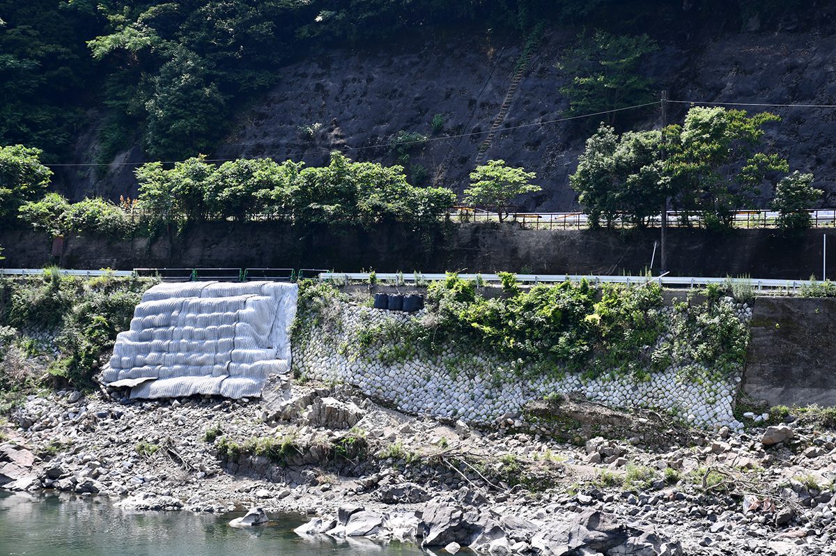 応急復旧された左岸側の護岸。その上を走るのが県道。県道の後ろにあるのが、代替路として活用中のJR肥薩線の線路（跡）