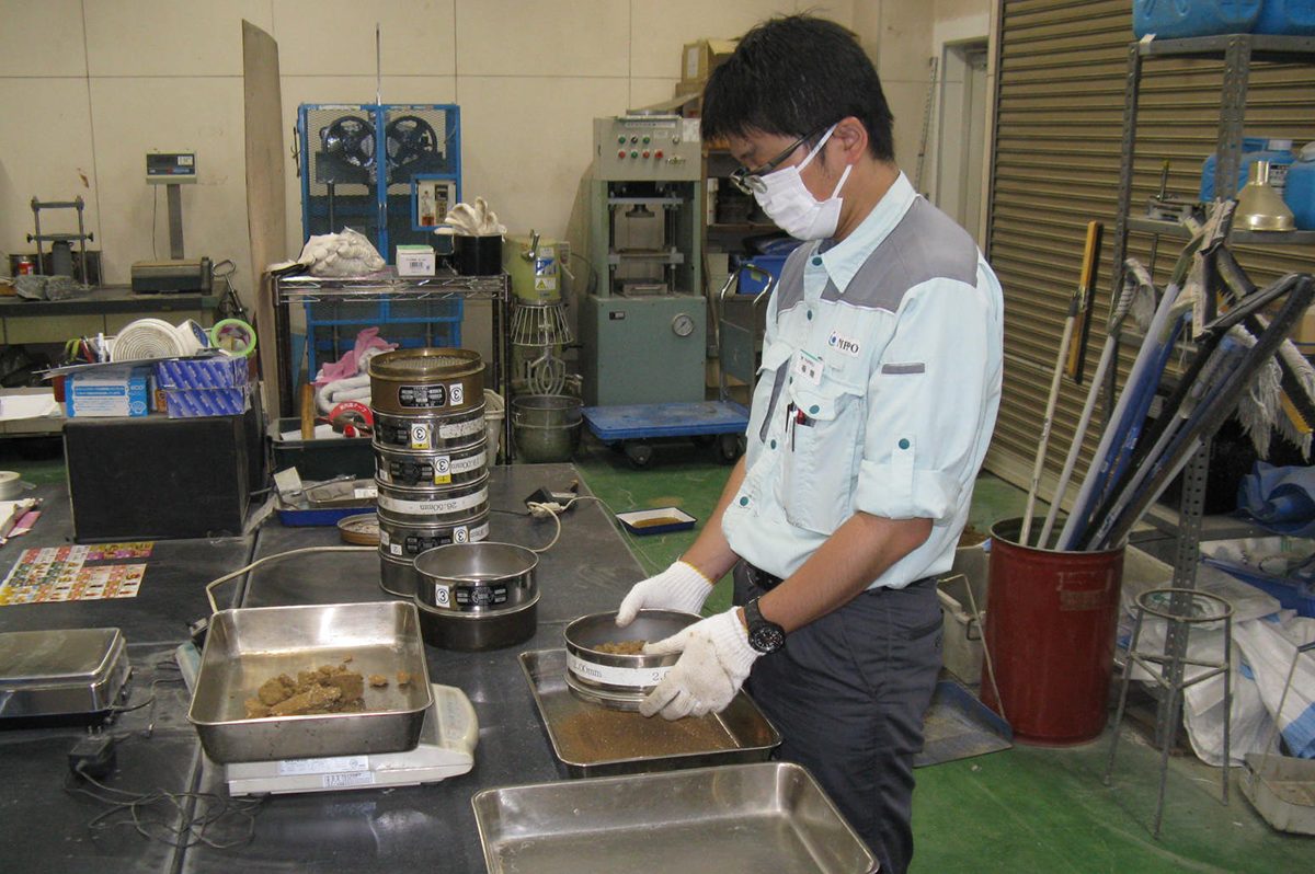 土の粒度試験（ふるい分け）を行っている福間さん