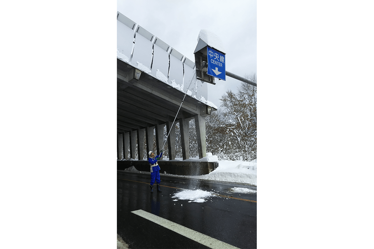 道路標識上の積雪を除去する作業の様子(横江さん提供)
