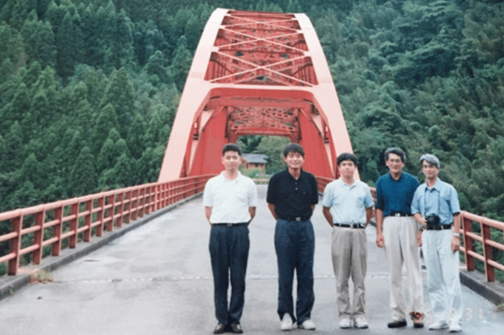 橋と撮影した写真のご提供をお願いすると、意外にあまりなかったそうで、福岡県橋梁建設課長時代の九州長大橋調査（1995年9月頃）で熊本県の内大臣橋に出向いた際の懐かしい1枚を＝左から福岡県職員、コンサル部長、角さん、九産大（故）吉村教授、同水田教授（現九産大 名誉教授）