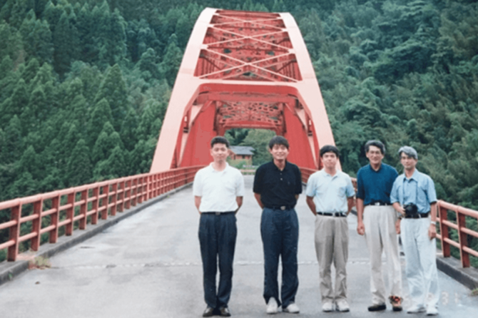 橋と撮影した写真のご提供をお願いすると、意外にあまりなかったそうで、福岡県橋梁建設課長時代の九州長大橋調査（1995年9月頃）で熊本県の内大臣橋に出向いた際の懐かしい1枚を＝左から福岡県職員、コンサル部長、角さん、九産大（故）吉村教授、同水田教授（現九産大 名誉教授）