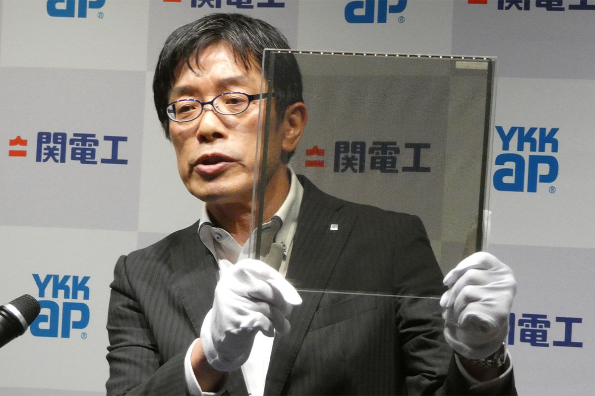 試作品のガラス型ペロブスカイトを持って説明する、YKK AP新規事業開拓部長の中谷卓也氏