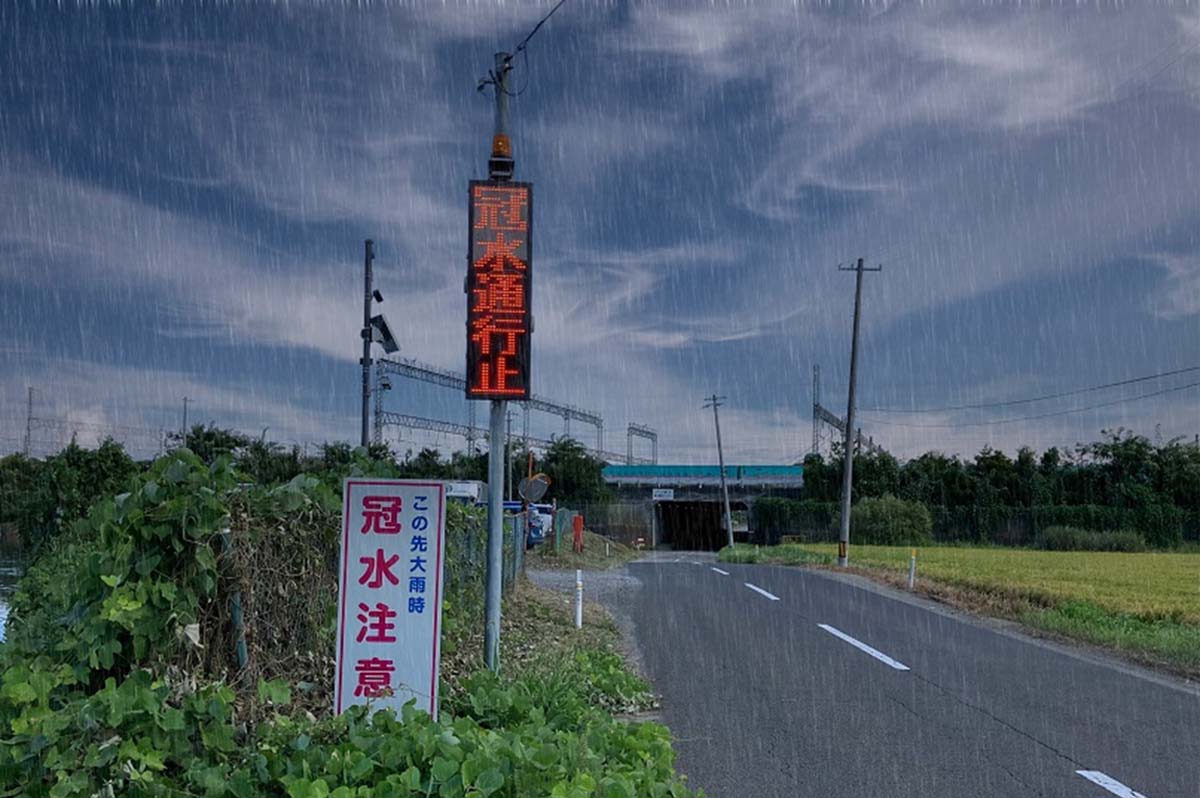 宮城県利府町の町道に設置された冠水通知型LED表示機システムと、従来の注意喚起看板(※雨天時のイメージ写真)