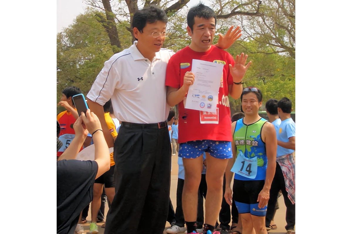 アンコールワットトライアスロンで日本人1位の猫ひろしさんとプレゼンターの北村晴男弁護士、後方は日本人2位の阿部氏