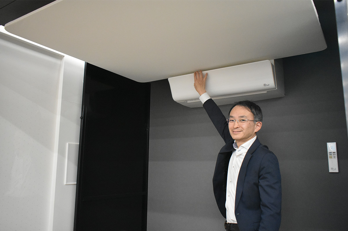 眠リッチ® (壁掛タイプ)の前で。室内は、風はないのに冷気を感じる不思議な感覚。