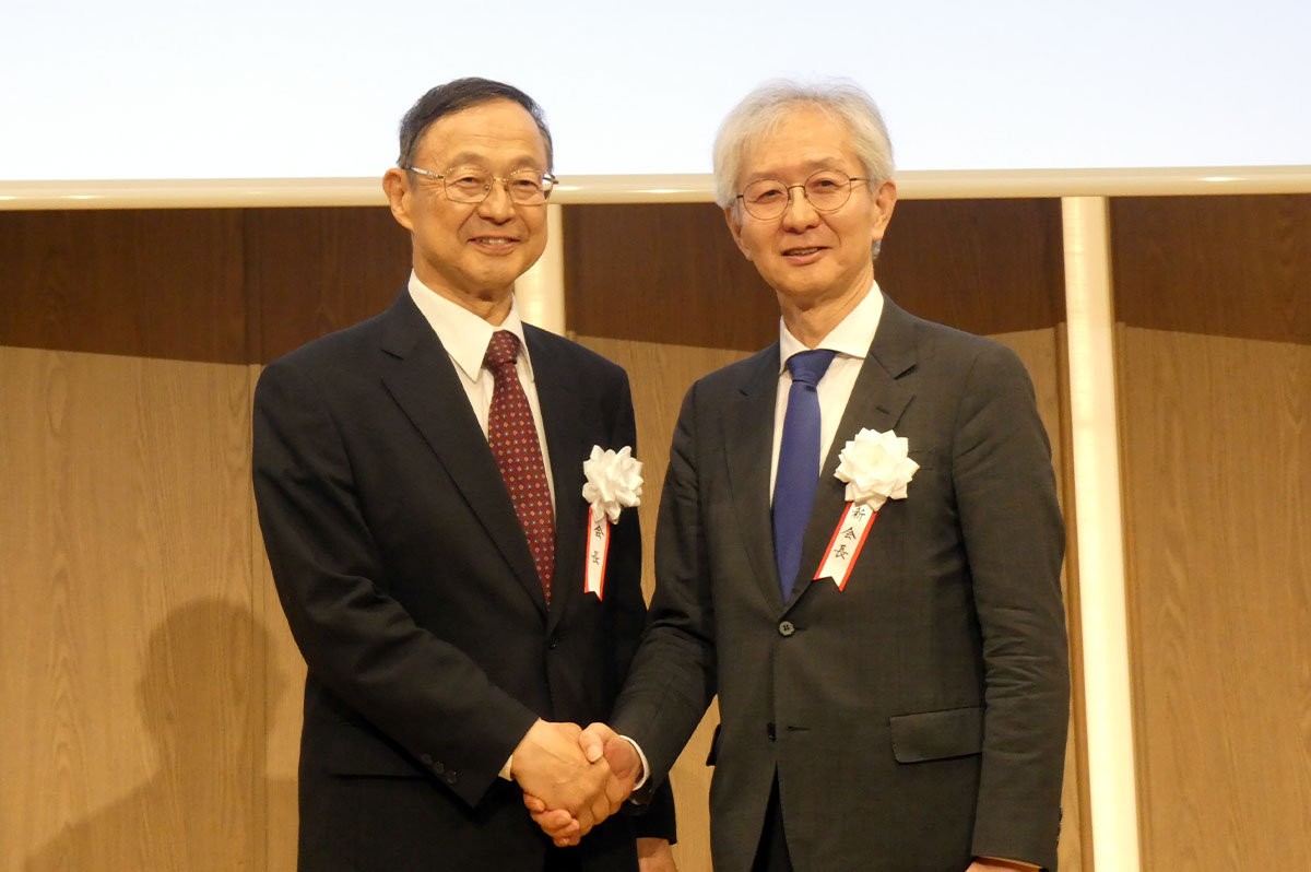 池内幸司前会長と小澤一雅新会長ががっちりと握手